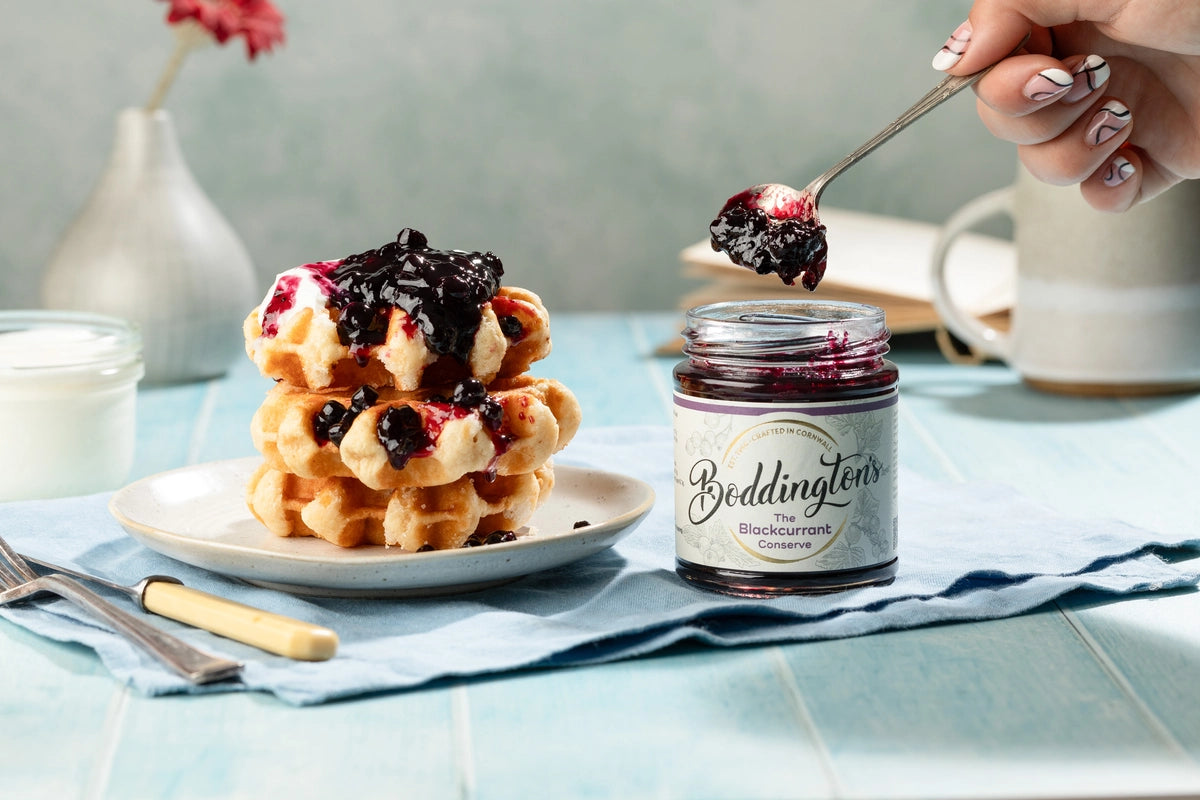 Stack of waffles having blackcurrant jam spooned on from a jar of Boddington's Blackcurrant conserve.