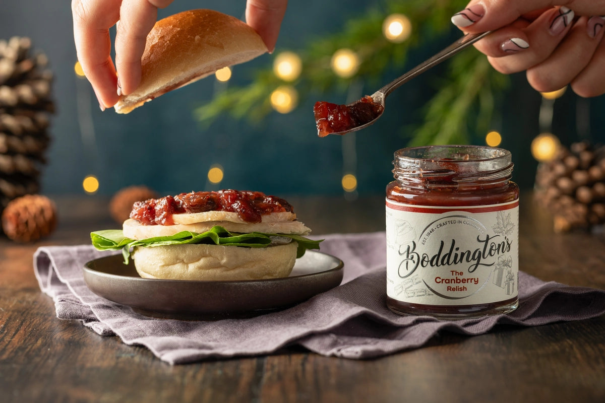Person adding Boddington's Cranberry Relish to a turkey sandwich