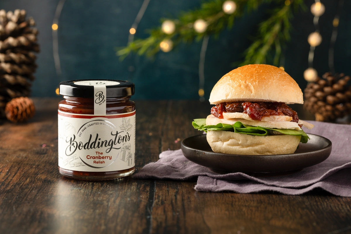 Turkey Burger with a jar of Boddington's Cranberry Relish on a wooden surface with festive decorations.