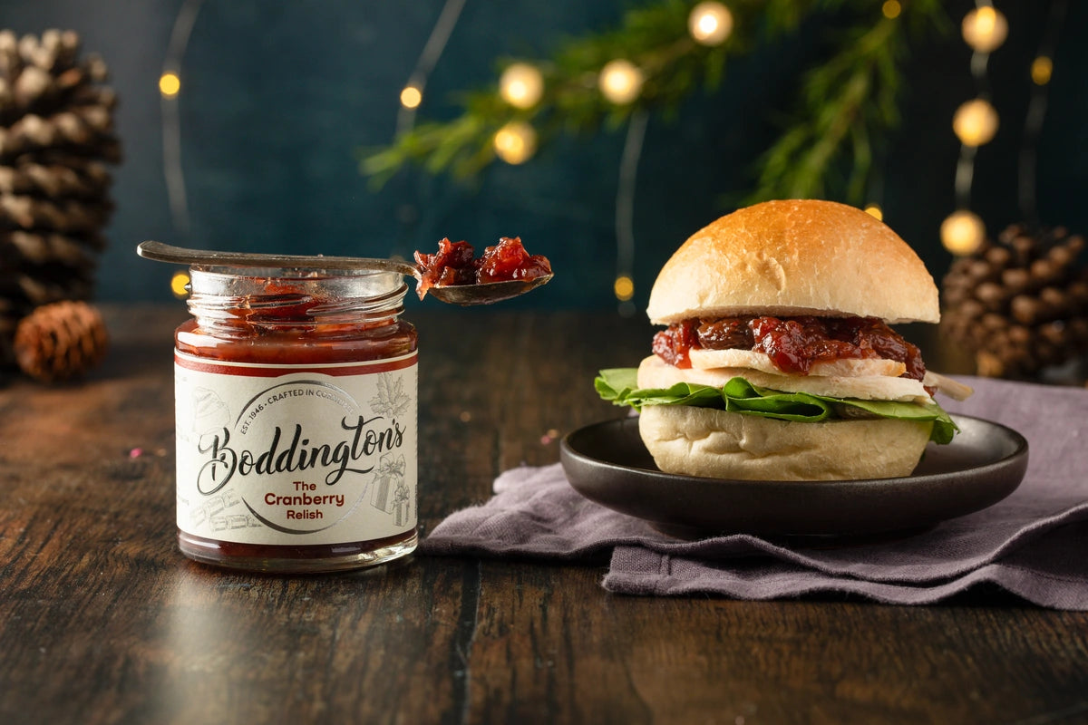 Turkey Burger with an open jar of Boddington's Cranberry Relish on a wooden surface with festive decorations.