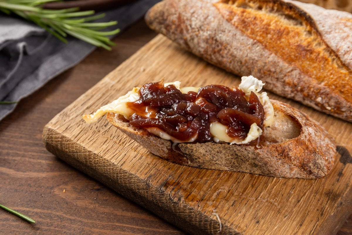 Bread with Boddington's Red Onion Relish and camembert cheese on a wooden cutting board