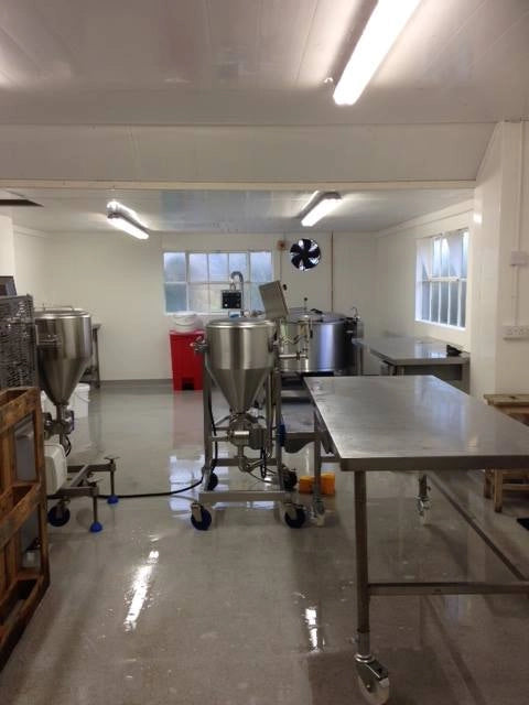 Clean industrial jam kitchen with stainless steel equipment and white walls.