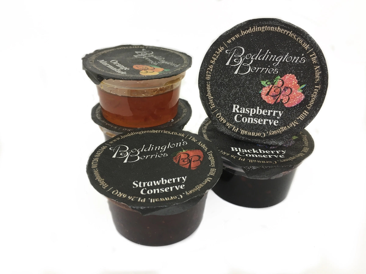 Four individual pots of Boddington's Berries jam with black lids on a white background