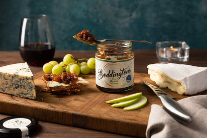Cheeseboard with Boddington's chutney, grapes, and other appetisers on a wooden board.