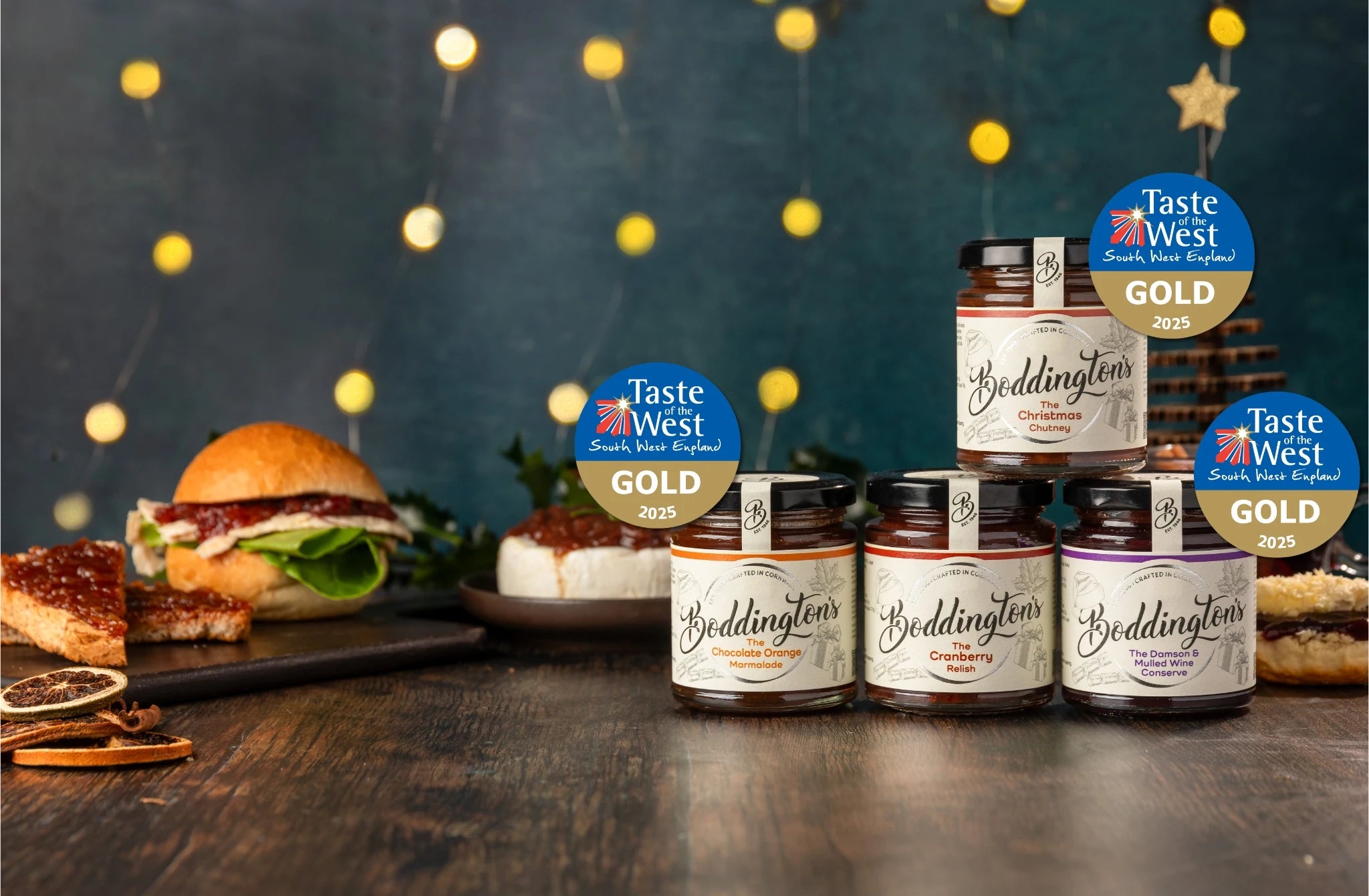 Jars of Boddington's festive range on a wooden table with a festive background along with their Taste of the West Awards.