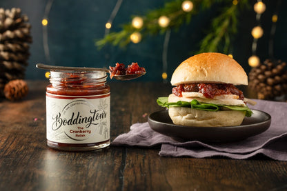 Turkey Burger with an open jar of Boddington's Cranberry Relish on a wooden surface with festive decorations.