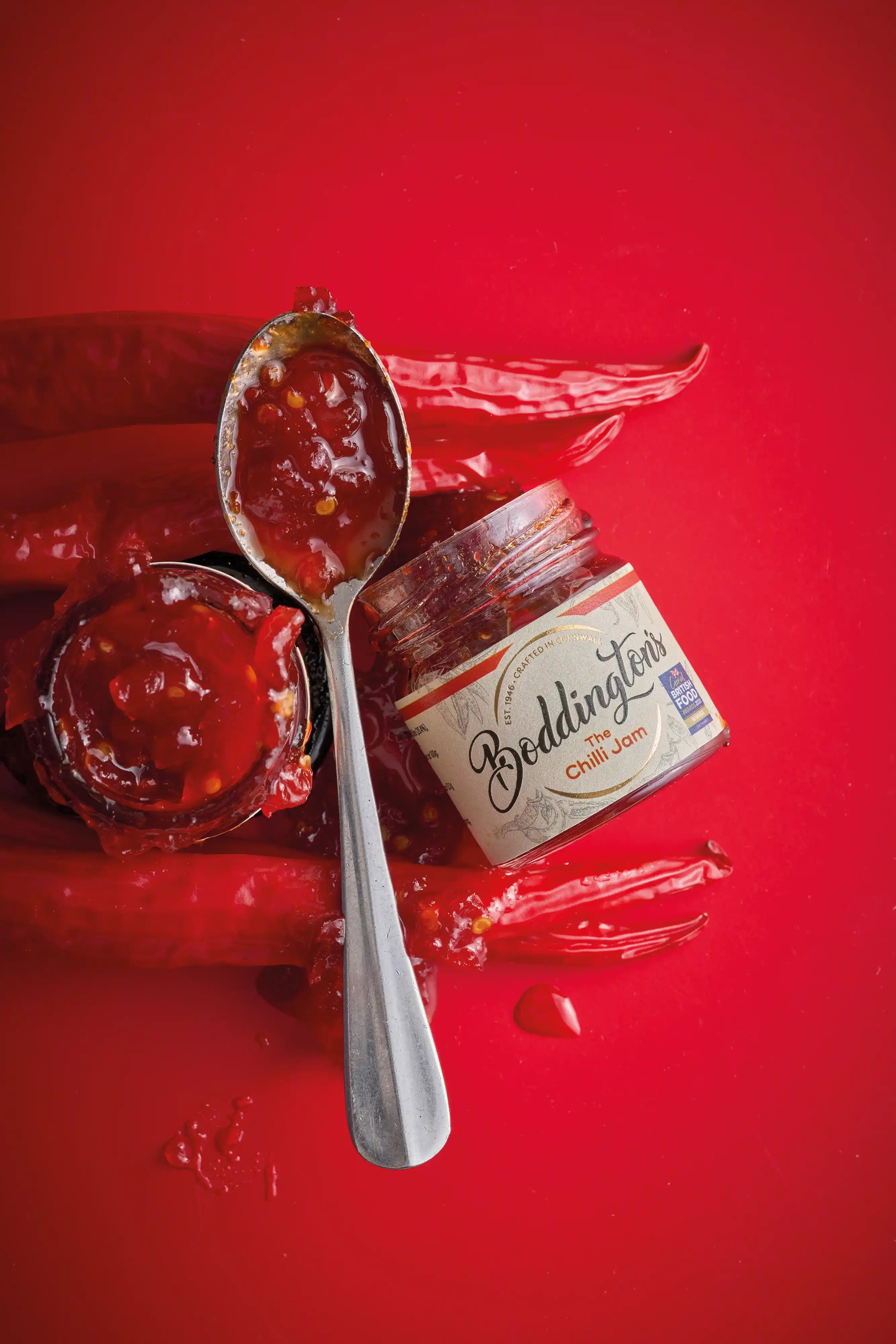 Jar of Boddington's chilli jam with a spoonful on a red background